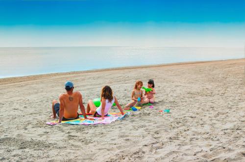 a group of people sitting on the beach at Fiordo Mare Vostrum in Isola Albarella