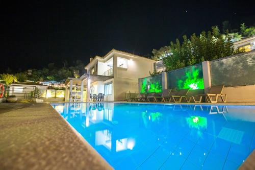 a villa with a swimming pool at night at Thealos Village aparthotel Lefkada in Lygia