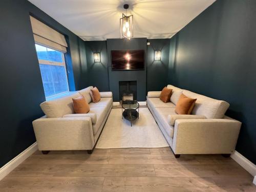 a living room with two couches and a fireplace at Luxury Cromer cottage with hot tub & log burner in Town in Cromer