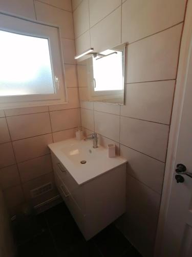 une salle de bain blanche avec un lavabo et une fenêtre dans l'établissement Gîte Au fil de l'eau, à Muides-sur-Loire