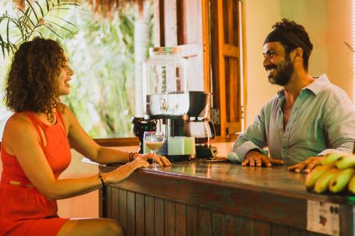 a man and woman sitting at a bar with a glass of wine at Aldea Che-Eek , con acceso a un club de playa privado in Bacalar
