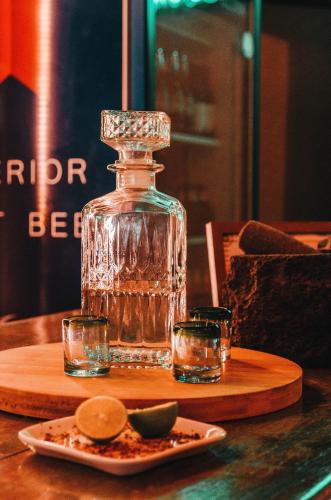 a glass bottle and two glasses on a table at Aldea Che-Eek , con acceso a un club de playa privado in Bacalar