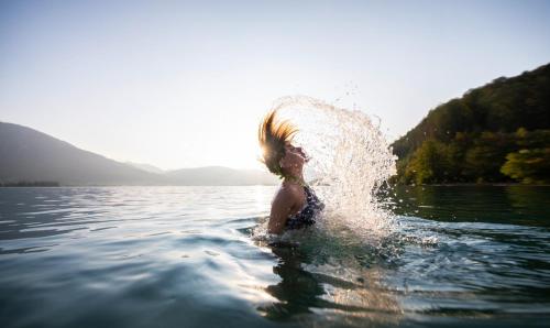 a woman splashing in the water in a lake at Hoferbauergut in Strobl