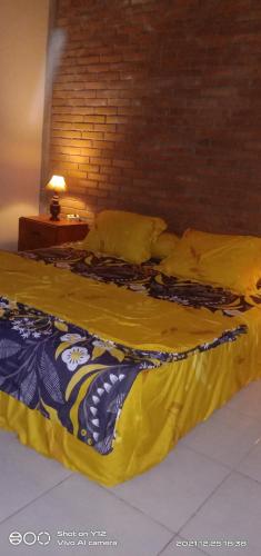 a bed with a yellow comforter and pillows on it at Homestay Durohman Borobudur in Mendut