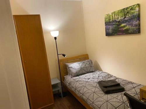 a small bedroom with a bed and a lamp at Cosy Ealing Homestay in London