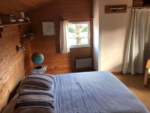 een slaapkamer met een bed in een kamer met een raam bij Maison familiale en bois avec piscine, proche du bassin in Gujan-Mestras