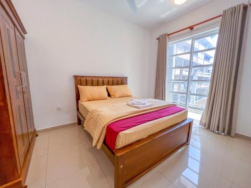 Bett in einem Zimmer mit einem großen Fenster in der Unterkunft LAR LUXURY APARTMENTS in Colombo