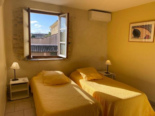 twee bedden in een kamer met een raam bij Le mas d'Orsan in Orsan