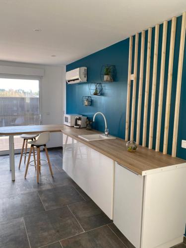 - une cuisine avec un évier et un mur bleu dans l'établissement Le Paradise, à Ville-le-Marclet