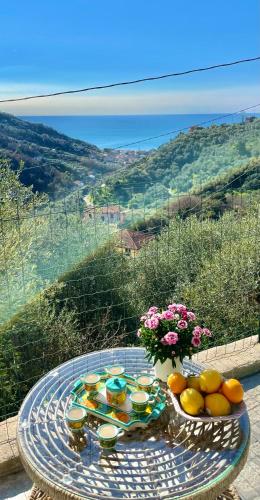 a glass table with a bowl of oranges and a vase of flowers at Foglie d'Argento in Moneglia