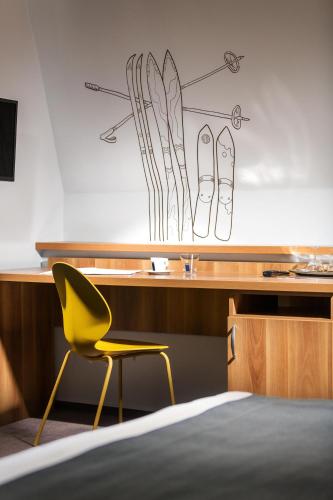 a yellow chair sitting in front of a desk at Wellness Hotel Grand in Špindlerův Mlýn