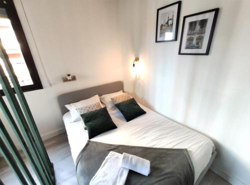 - une petite chambre avec un lit blanc et des oreillers verts dans l'établissement LE GUILHEMéRY - Canal du Midi - Free Parking, à Toulouse