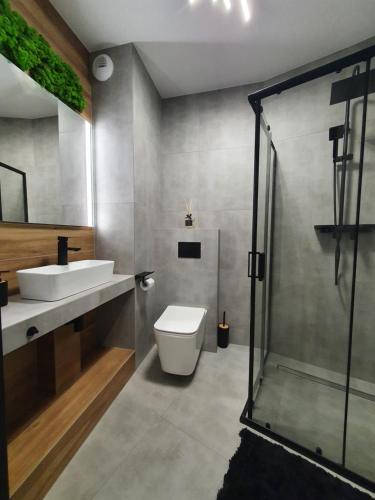 a bathroom with a toilet and a sink and a shower at Apartamenty HashtagWilda in Poznań