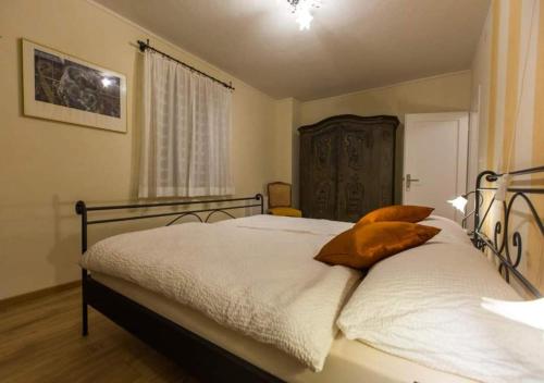 a bedroom with a bed with white sheets and orange pillows at Antica Osteria Ghiridone in Palagnedra