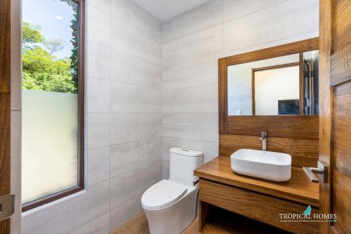 ein Badezimmer mit einem WC, einem Waschbecken und einem Spiegel in der Unterkunft Casa Coralis - NEW modern house with private pool in Potrero