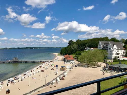 a beach with a pier and people sitting on the sand at Appartement _An der Seebruecke_ in Glücksburg