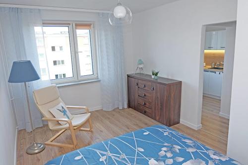 a bedroom with a bed and a chair and a dresser at A spacious apartment for holidays and weekends in Ełk