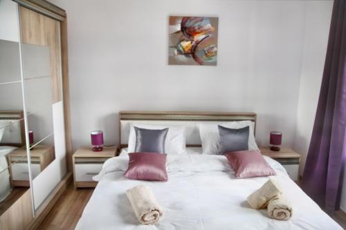 a bedroom with a large white bed with pink pillows at Luxury Downtown Apartment in Cluj-Napoca