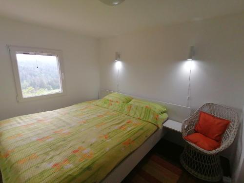 a bedroom with a bed and a window and a chair at Tara Suncani sjaj-planinska kuca in Šljivovica