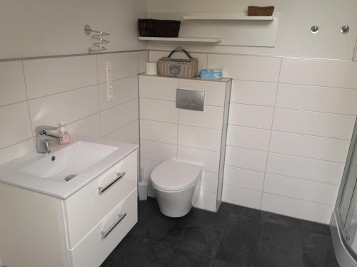 a white bathroom with a toilet and a sink at Megis Ferien Unterkunft 