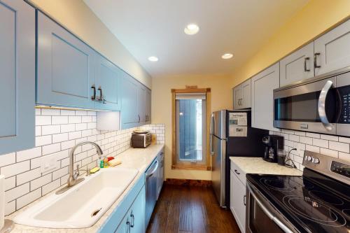a kitchen with blue cabinets and a sink and a microwave at Bellflower Trout House in Vail