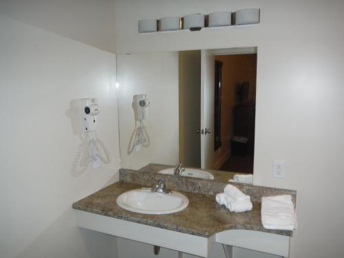 a bathroom with a sink and a mirror at Motel Beausejour in Neguac