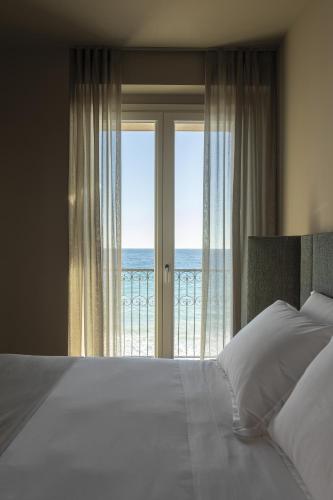 a bedroom with a bed and a view of the ocean at Hotel Windsor in Laigueglia