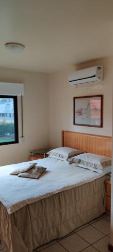 1 dormitorio con 1 cama grande con sábanas blancas y ventana en Apto Cond. Porto Ventura 3 quartos, en Florianópolis
