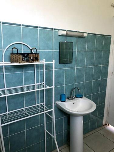 baño con lavabo y pared de azulejos azules en Bel appartement à Damencourt, en Le Moule