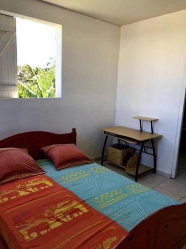 1 dormitorio con cama, mesa y ventana en Bel appartement à Damencourt, en Le Moule