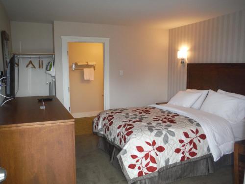 a hotel room with a bed and a dresser at Motel Beausejour in Neguac
