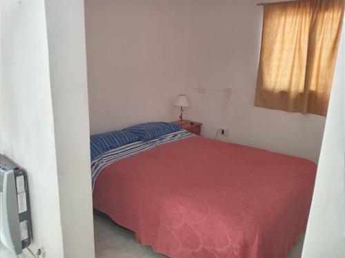 a bedroom with a red bed and a window at Lo de Juana in Trelew