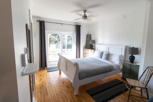 ein weißes Schlafzimmer mit einem Bett und einem Fenster in der Unterkunft La Ruelle Hébergement in Saint-Siméon