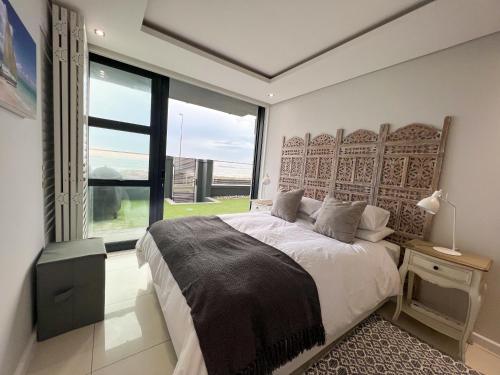 1 dormitorio con cama y ventana grande en Seacrest Luxury Beachfront Apartment - Blouberg Beach, en Bloubergstrand