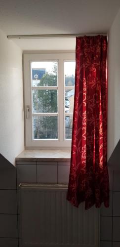 a window with a red curtain and a radiator at Villa Hoffnung in Bad Elster