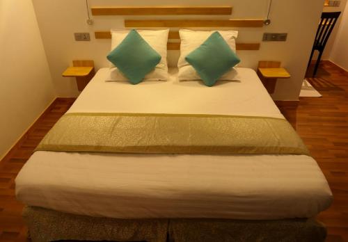 een slaapkamer met een bed met 2 groene kussens bij AYIRA Maldives in Feridhoo