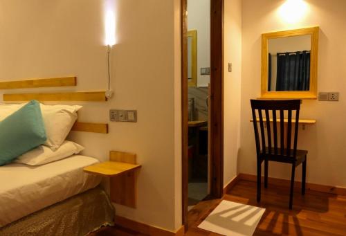a room with a bed and a chair and a mirror at AYIRA Maldives in Feridhoo
