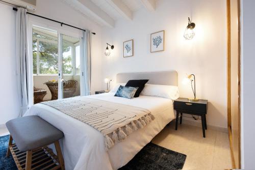 a white bedroom with a large bed and a window at Villa Eden Alcudia, near the beach with pool in Alcudia