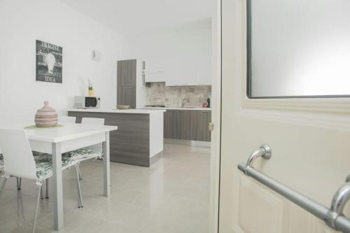 a kitchen with a table and a white table and chairs at Nuovo trilocale vicino centro/mare in Santa Teresa Gallura