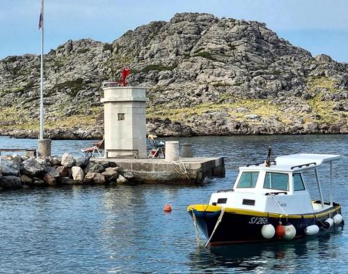 a small boat in the water near a lighthouse at Casa al mare in Sveti Juraj
