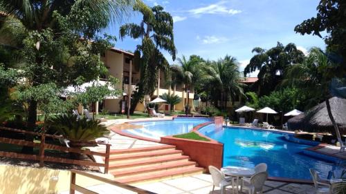 a pool at a resort with tables and chairs at Solar Pipa Praia Flats in Pipa