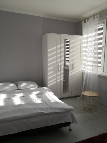 biała sypialnia z łóżkiem i oknem w obiekcie Różowe sny w Kłodzku