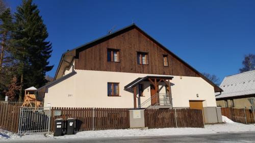 eine große weiße Scheune mit einem Holz in der Unterkunft Haus Tolštejn in Jiřetín pod Jedlovou