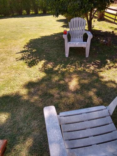 a white bench sitting in a yard next to a tree at Complejo Viejo Sulky in Mina Clavero