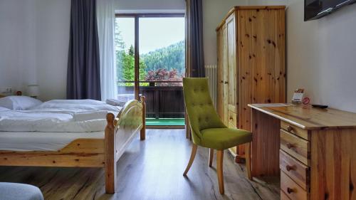 um quarto com uma cama, uma secretária e uma janela em Hotel Stierer em Ramsau am Dachstein
