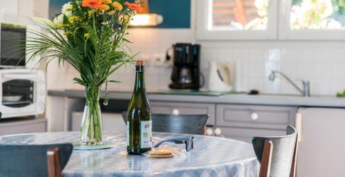 - une bouteille de vin assise sur une table avec un vase de fleurs dans l'établissement Grand LARGE FACE A LA PLAGE TRESTEL, à Trévou-Tréguignec
