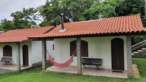 a small house with a red roof and a hammock at Pousada Tapera in Penedo