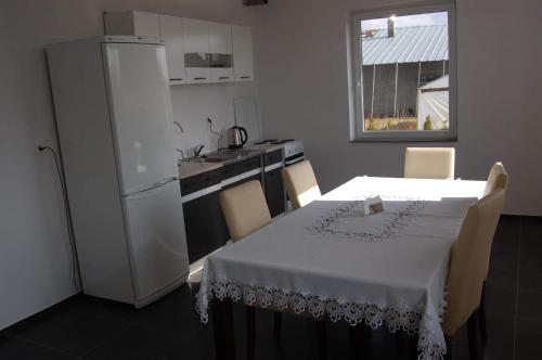 a kitchen with a table and a white refrigerator at Willa Rosa - Dom dla 20 osób z jacuzzi i sauną ogrodową Kaszuby in Bukowina