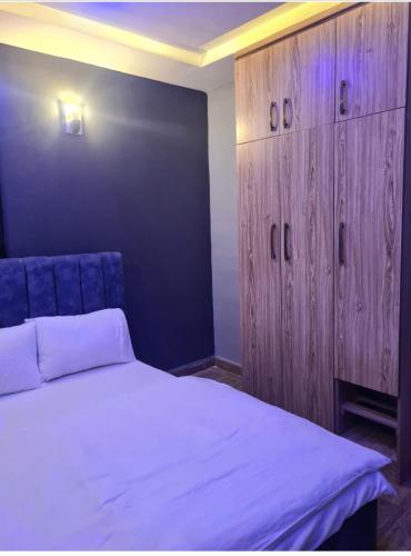 a bedroom with a white bed and wooden cabinets at Wine House, Maitama, Abuja in Abuja