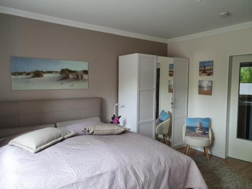 a bedroom with a large bed and a chair at Appartement Relax Sankt Peter Ording in Sankt Peter-Ording